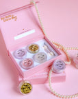 Makeup set with small jars and applicators in a pink box on a pink background