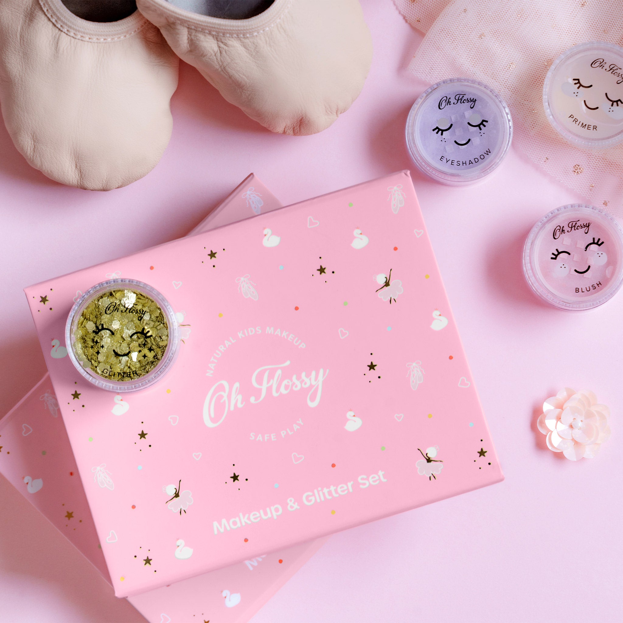 Makeup and glitter set with 'Oh Flossy' branding on a pink background
