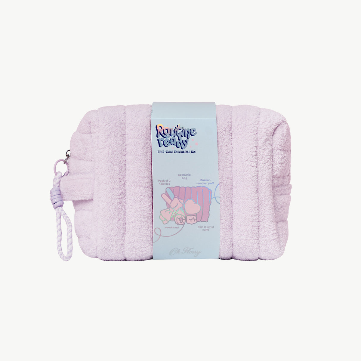 A light lilac plush cosmetic pouch with a matching wrist strap, wrapped in a light blue paper band featuring the 'Routinely Ready' brand logo and product details.